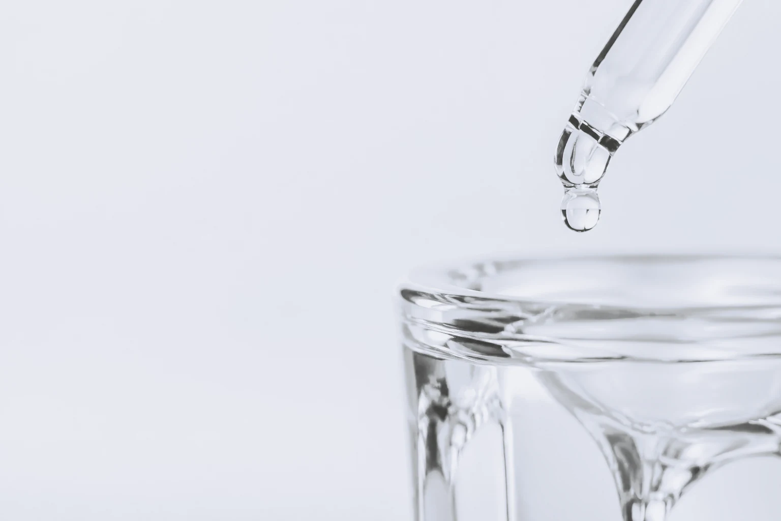A clear droplet held at the tip of a glass pipette